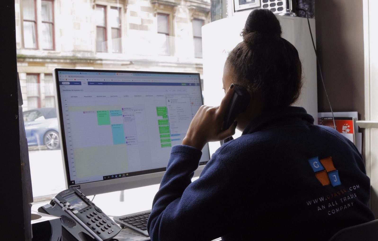 G Jassal employee on the phone and using Commusoft's job scheduling feature on desktop