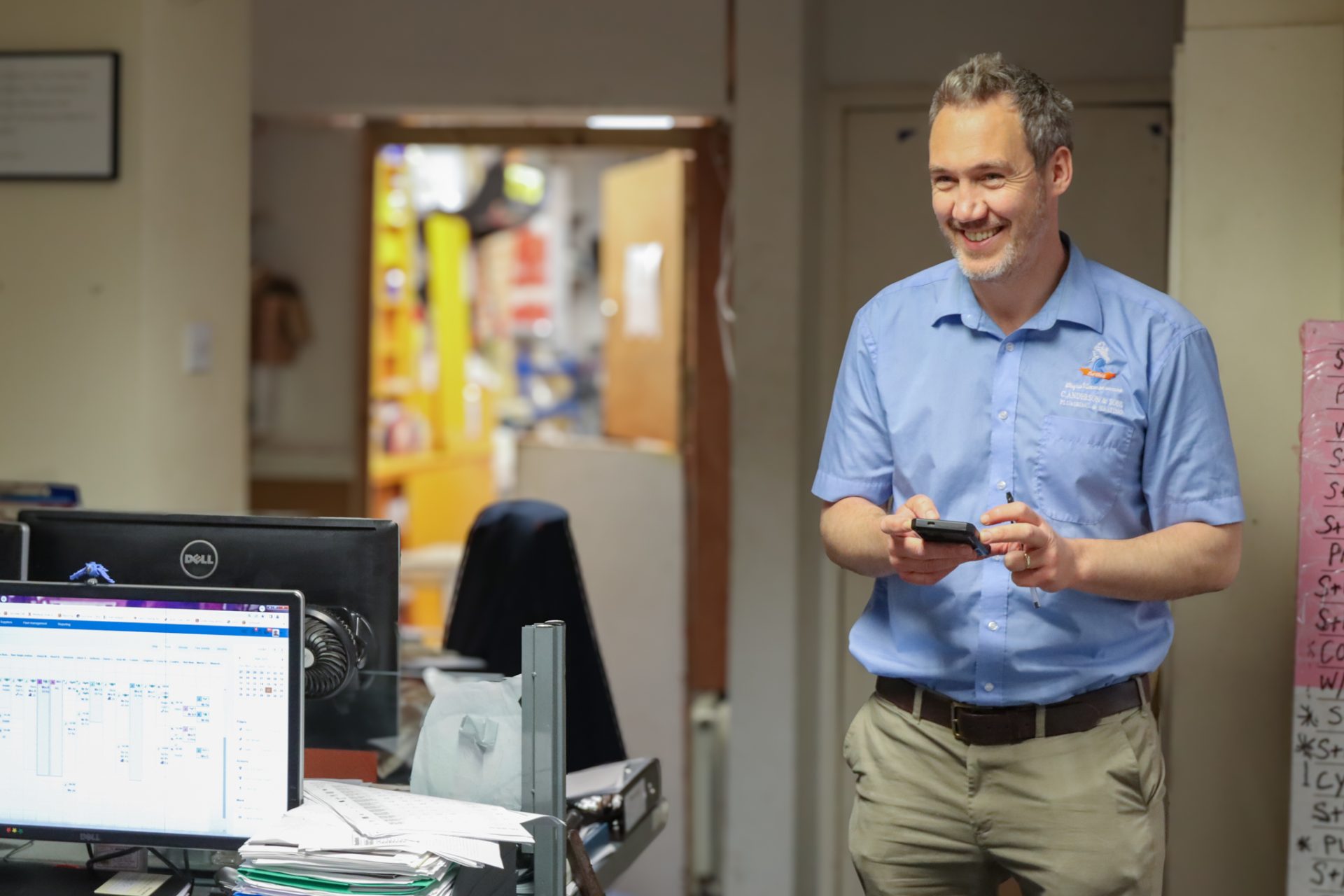 Crawford Anderson from C. Anderson & Sons holding a mobile and smiling in the company's office