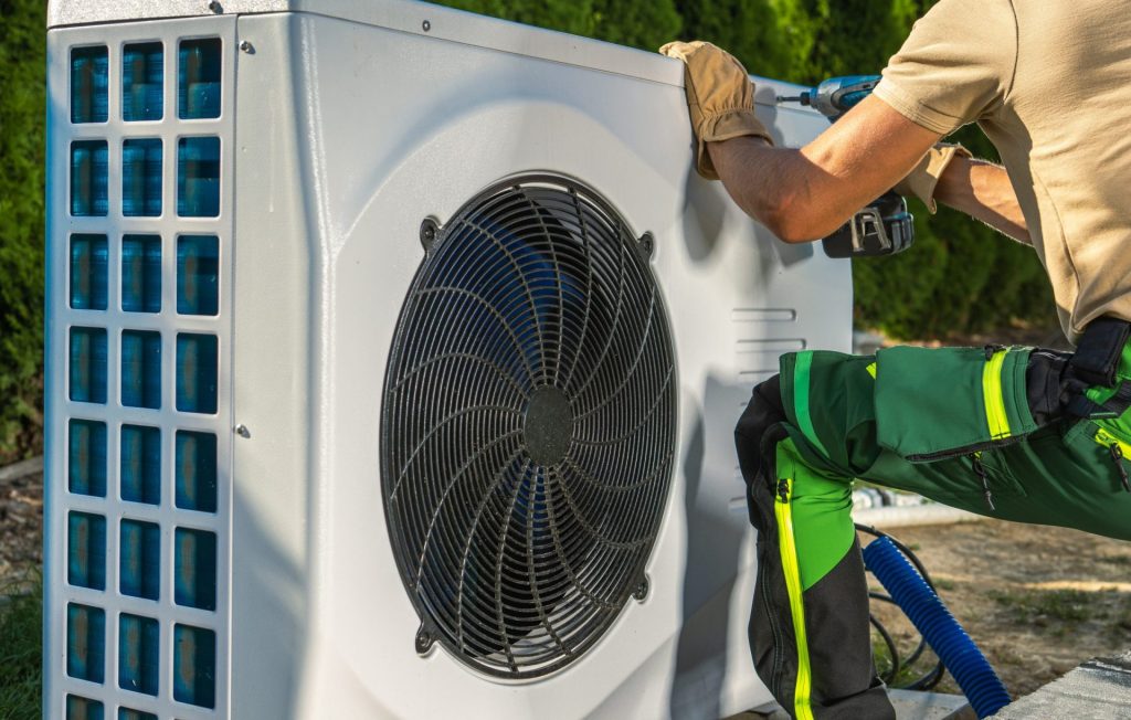 Engineer working on a HVAC system outside with a power drill
