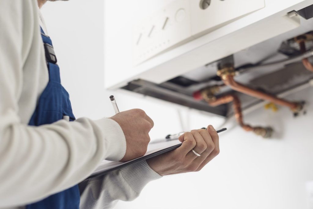 Engineer making notes on a clipboard with a boiler in the background