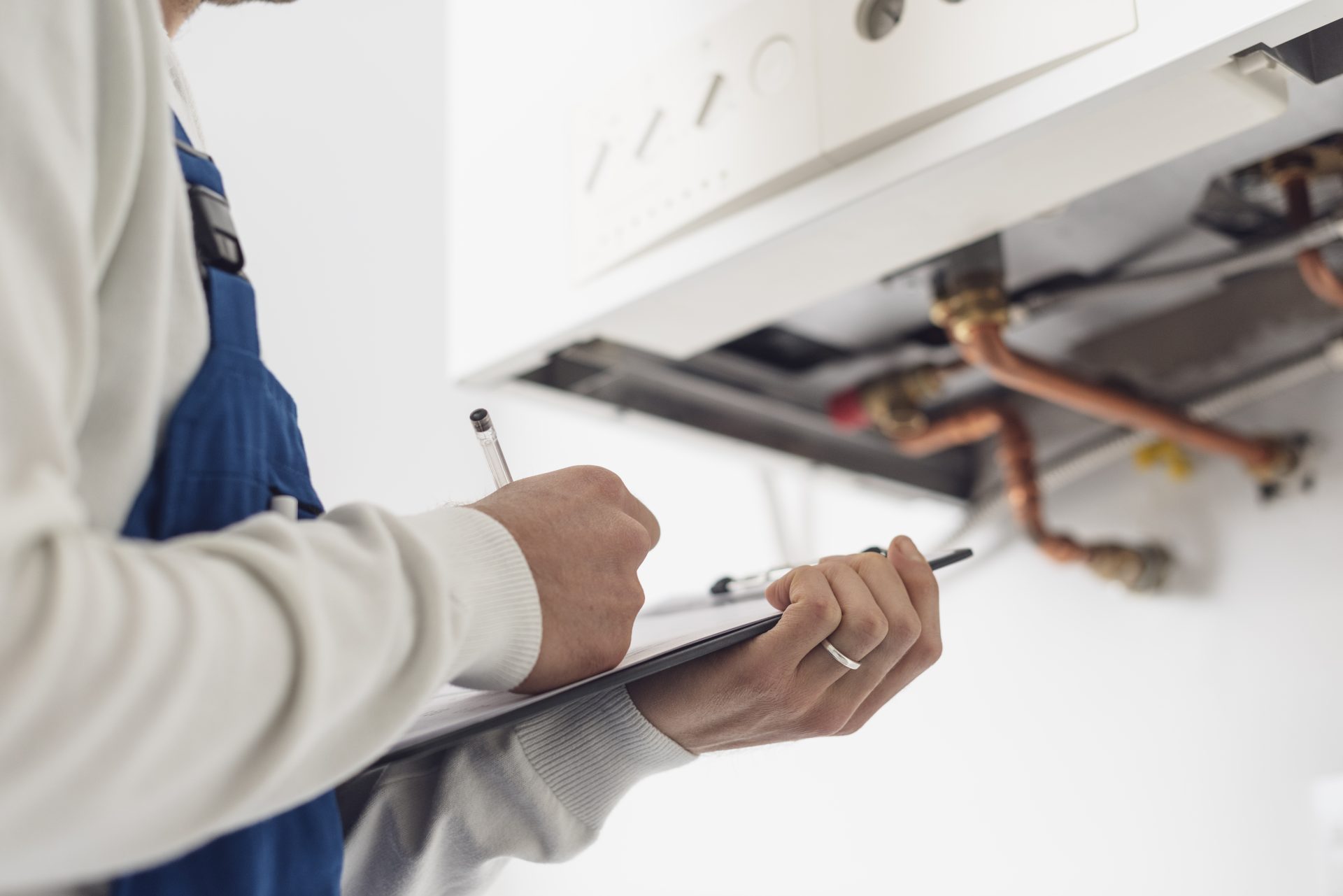 Engineer making notes on a clipboard with a boiler in the background