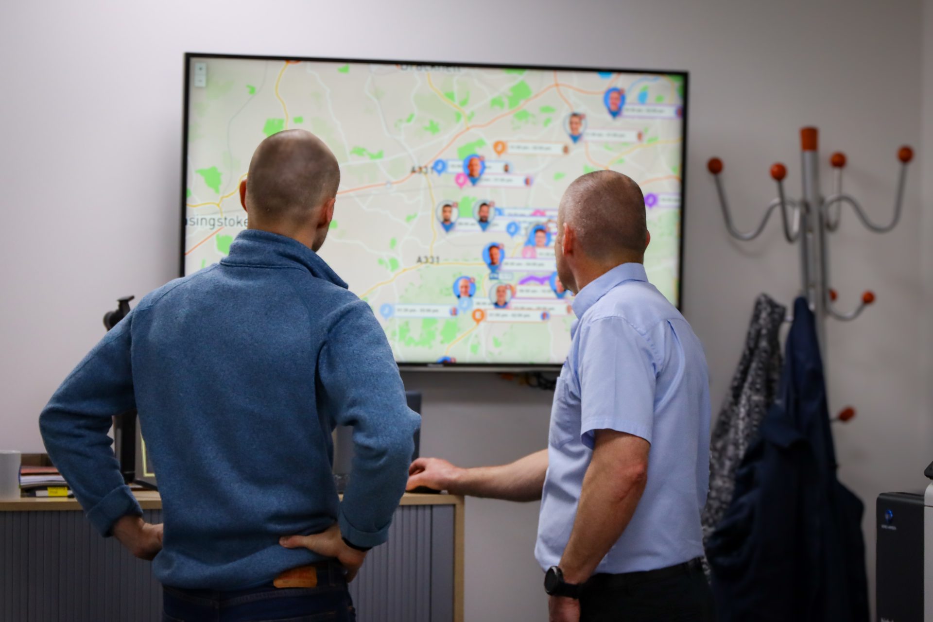 Employees looking at Commusoft's real-time tracking feature on a large television screen
