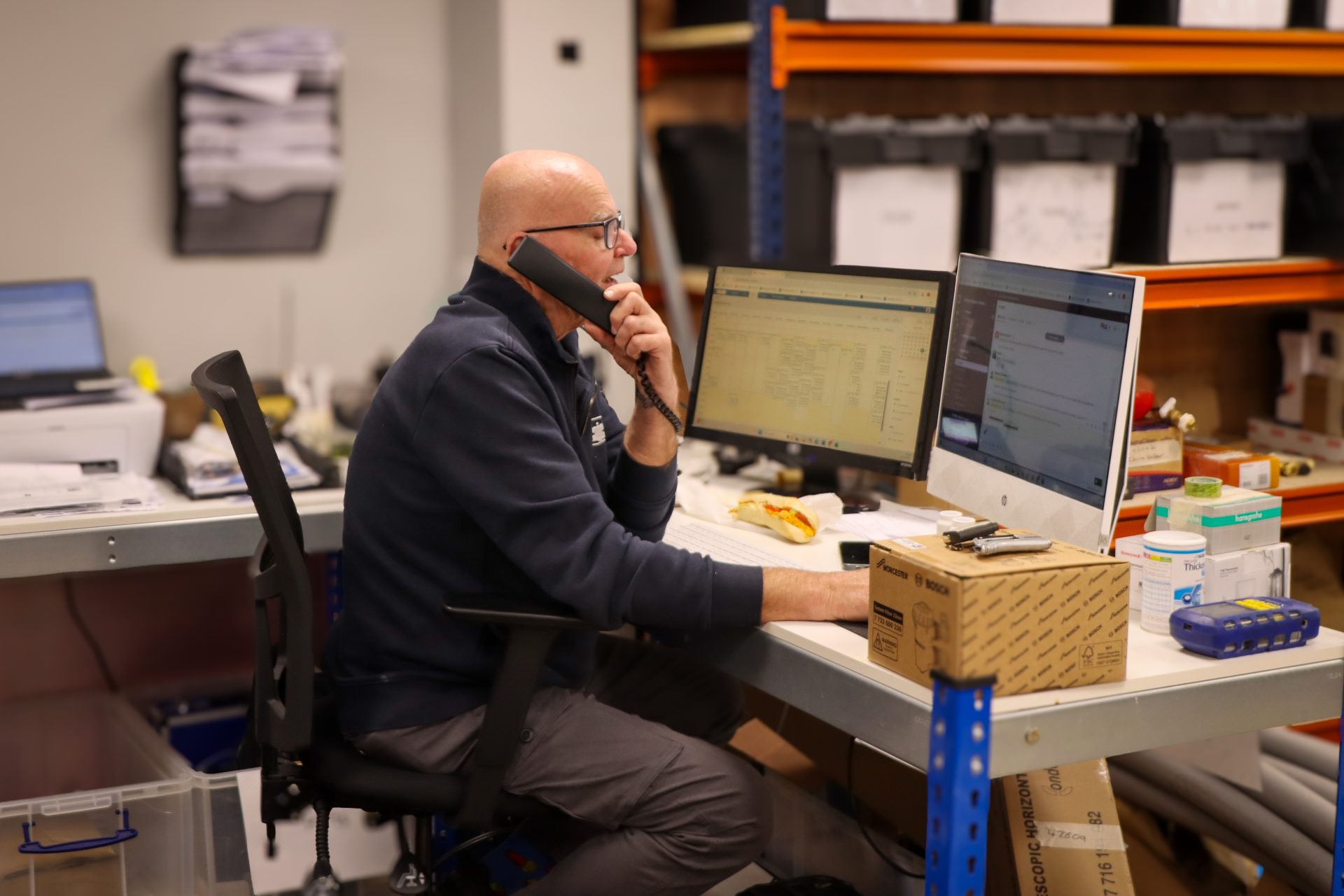 Employee working at their desk in a warehouse while on the phone