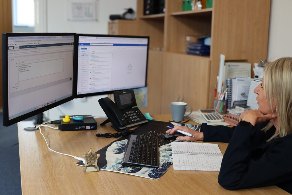 Woman working at computer and taking notes