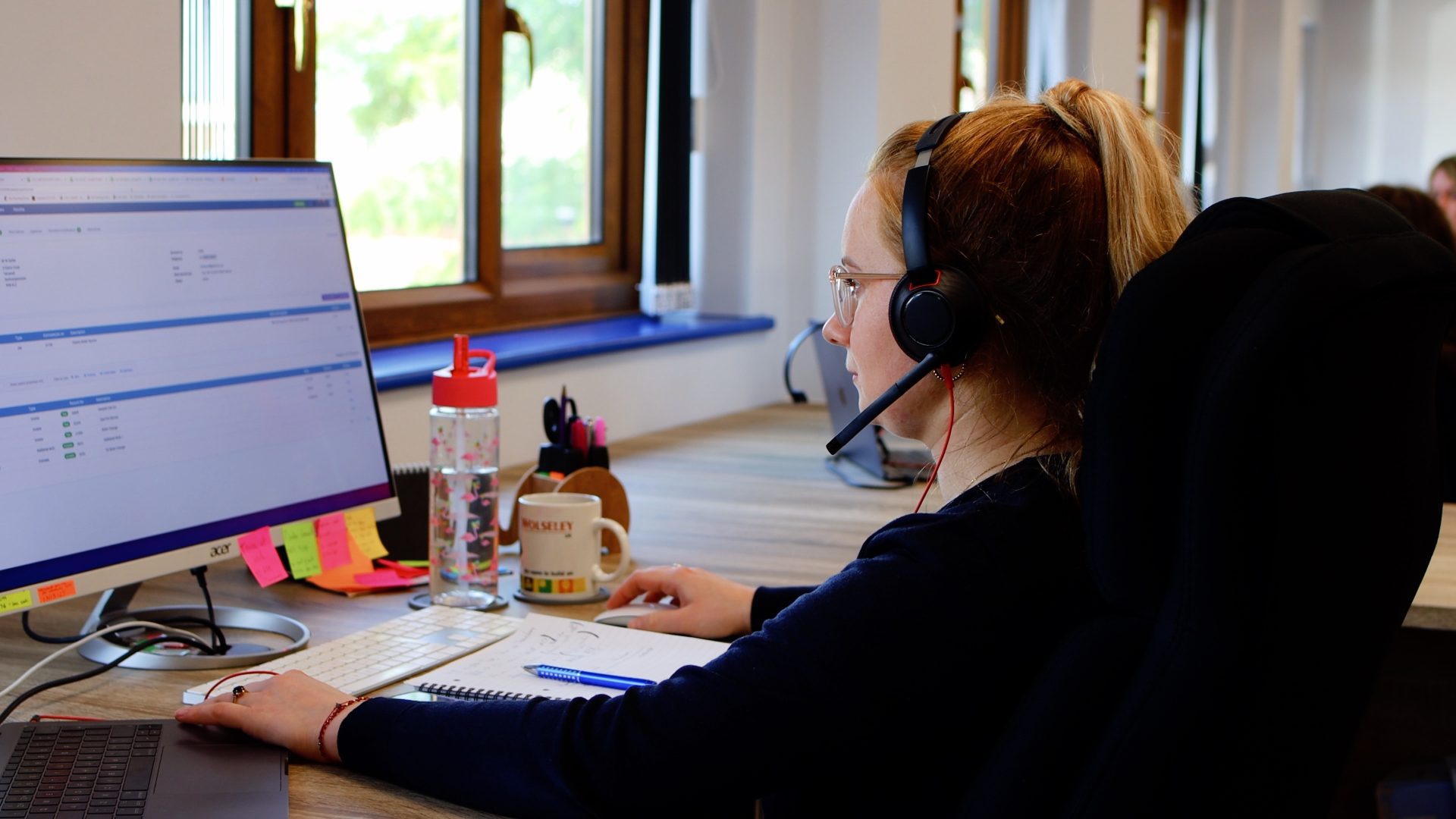 Employee with headset working on Commusoft on their desktop