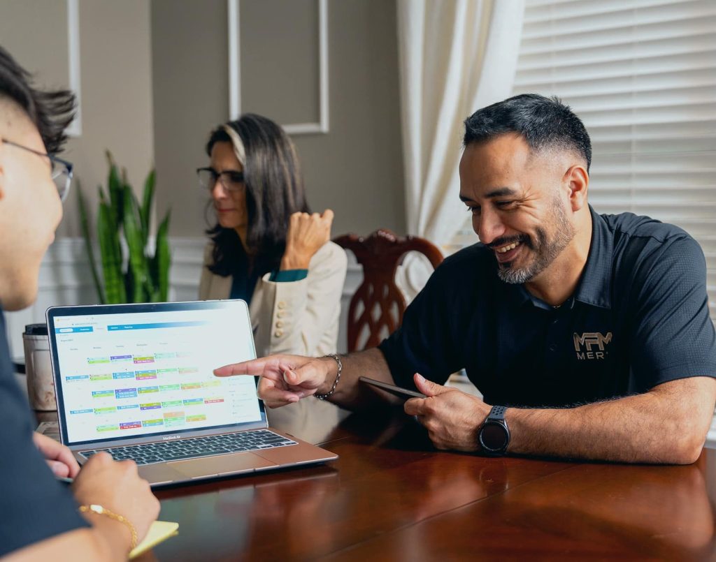Merit Facility Management team members laughing and looking at a laptop