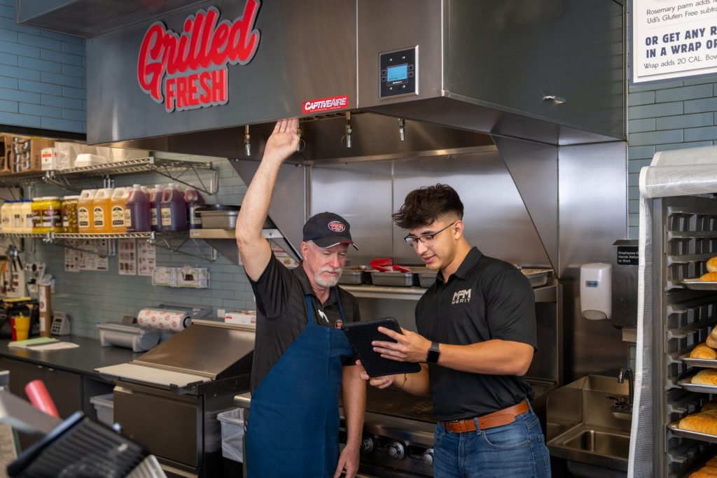 Merit Facility Management team member showing Grilled Fresh employee information on an iPad