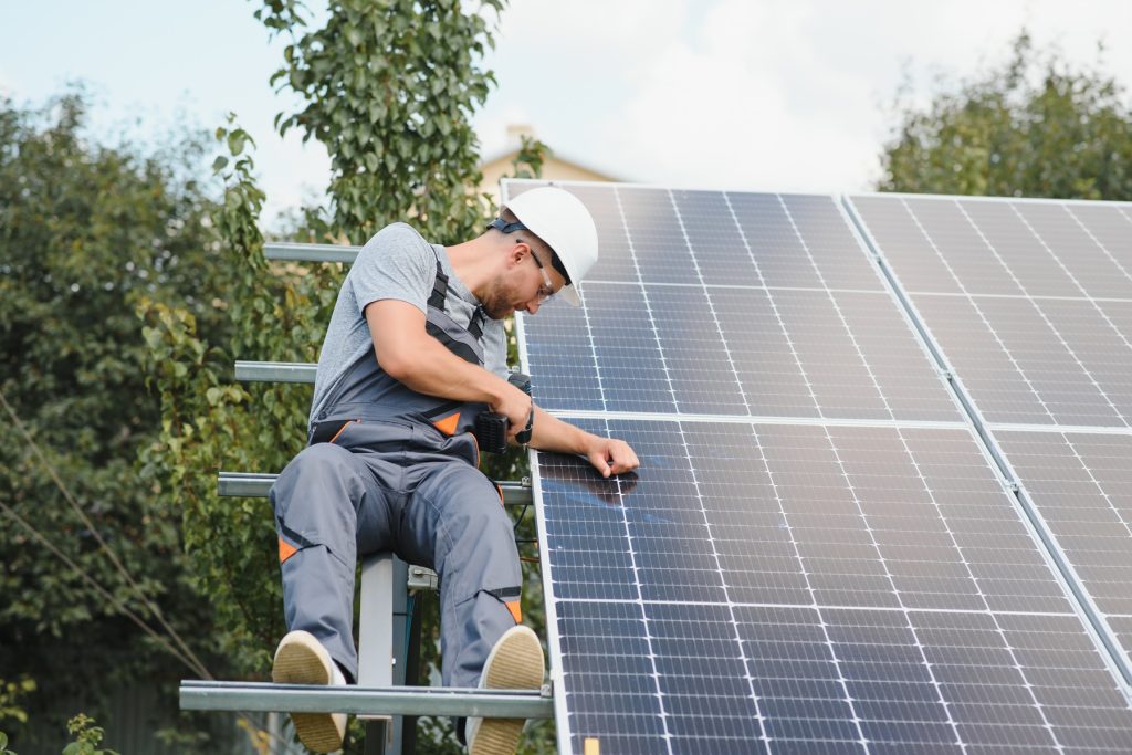 Man in a protective helmet working on solar panels