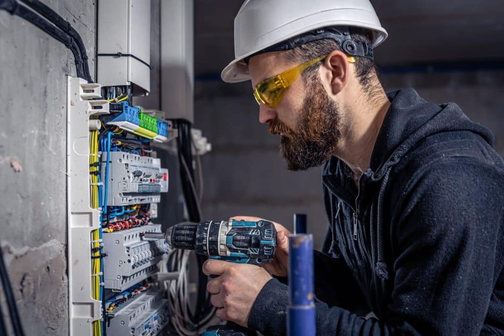 Male electrician works in a switchboard